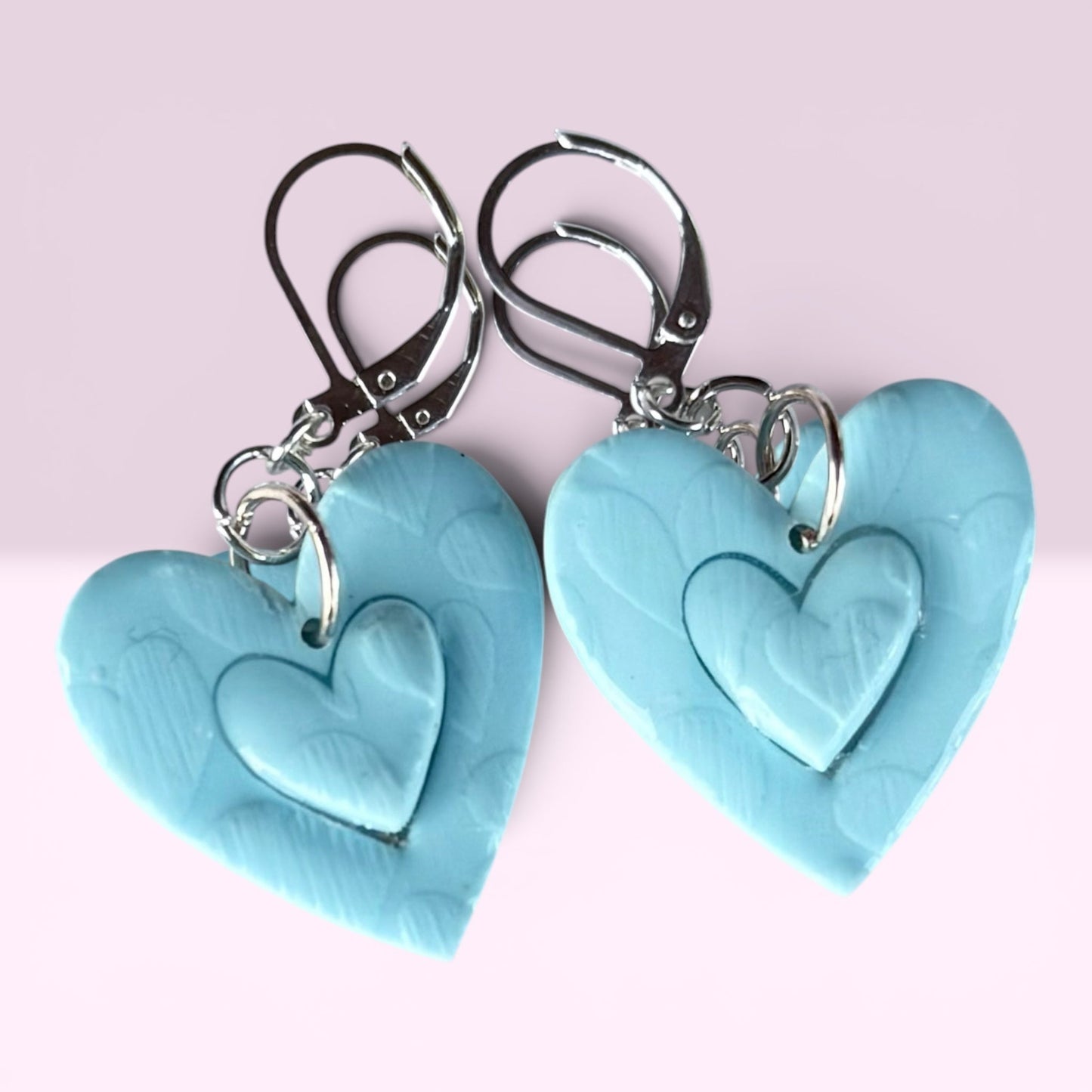 Blue Bottle Crafts handcrafted light blue polymer clay heart earrings with layered texture and silver metal findings.
